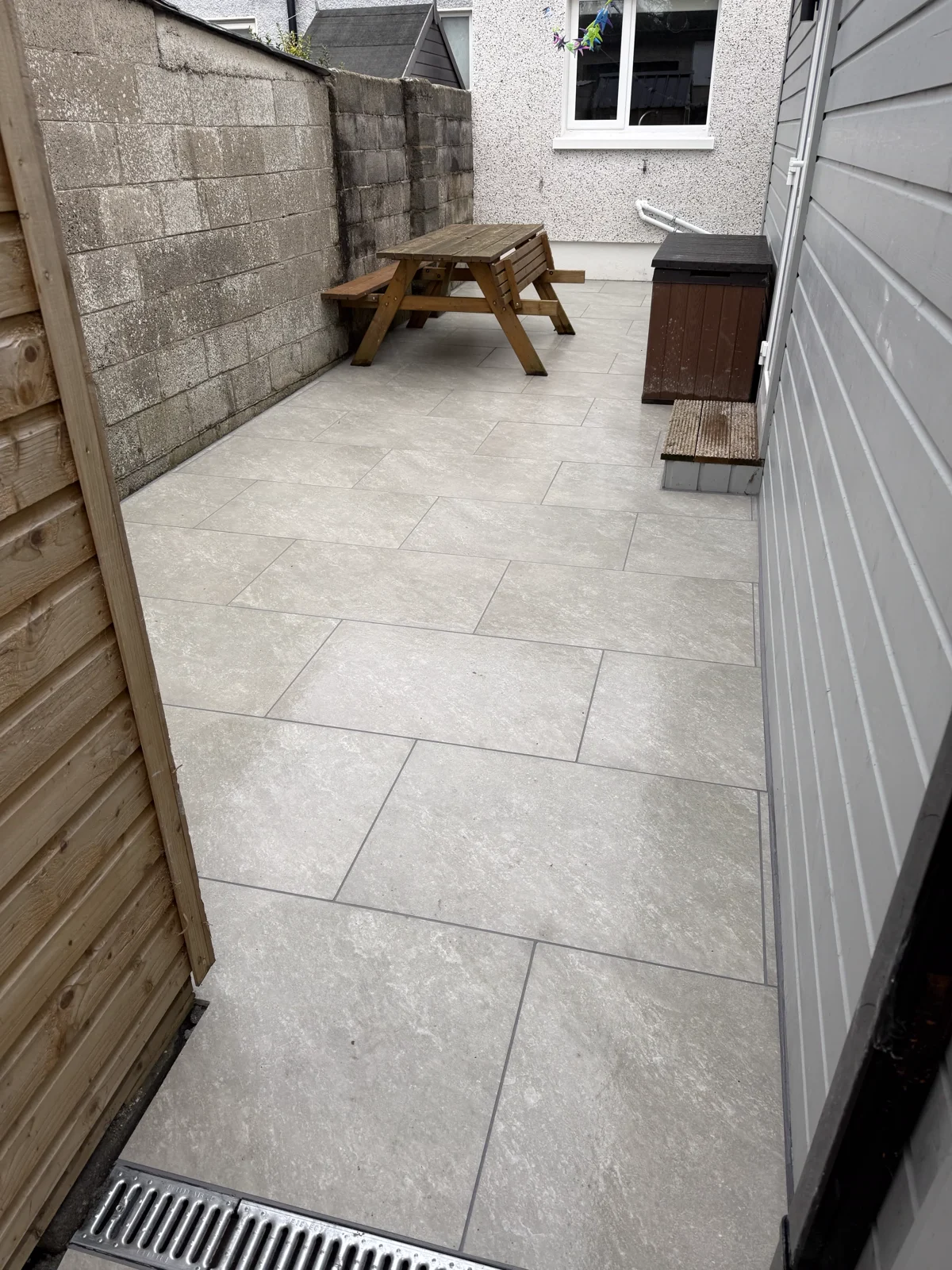 Completed porcelain courtyard paving beside a picnic table.