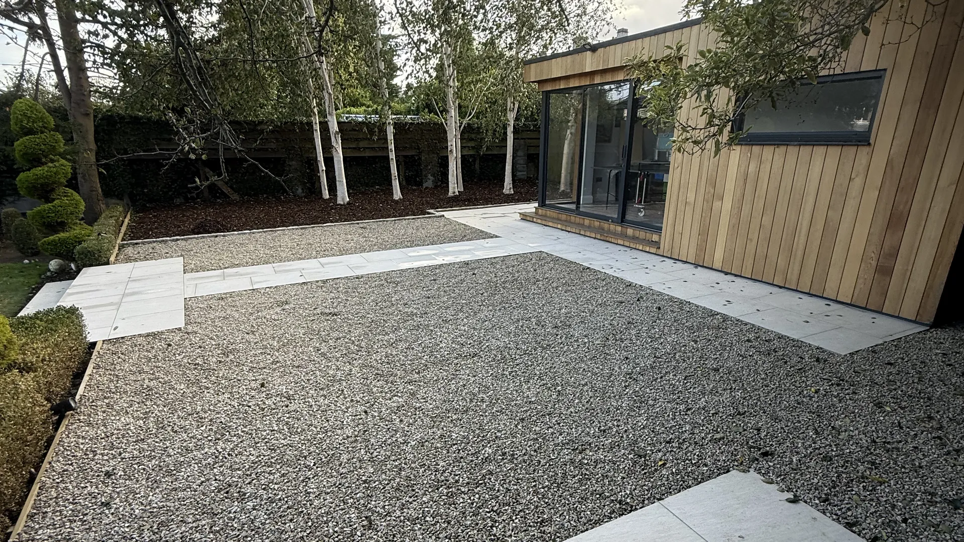 Finished Apex garden: porcelain paths, gravel panels and a cedar garden room.